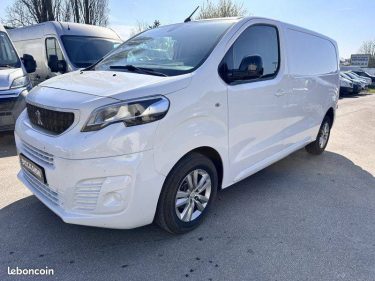 Fourgon blanc : Un utilitaire blanc de profil garé à l'extérieur.