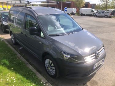 Minivan gris : Un véhicule familial gris garé le long d'une pelouse.