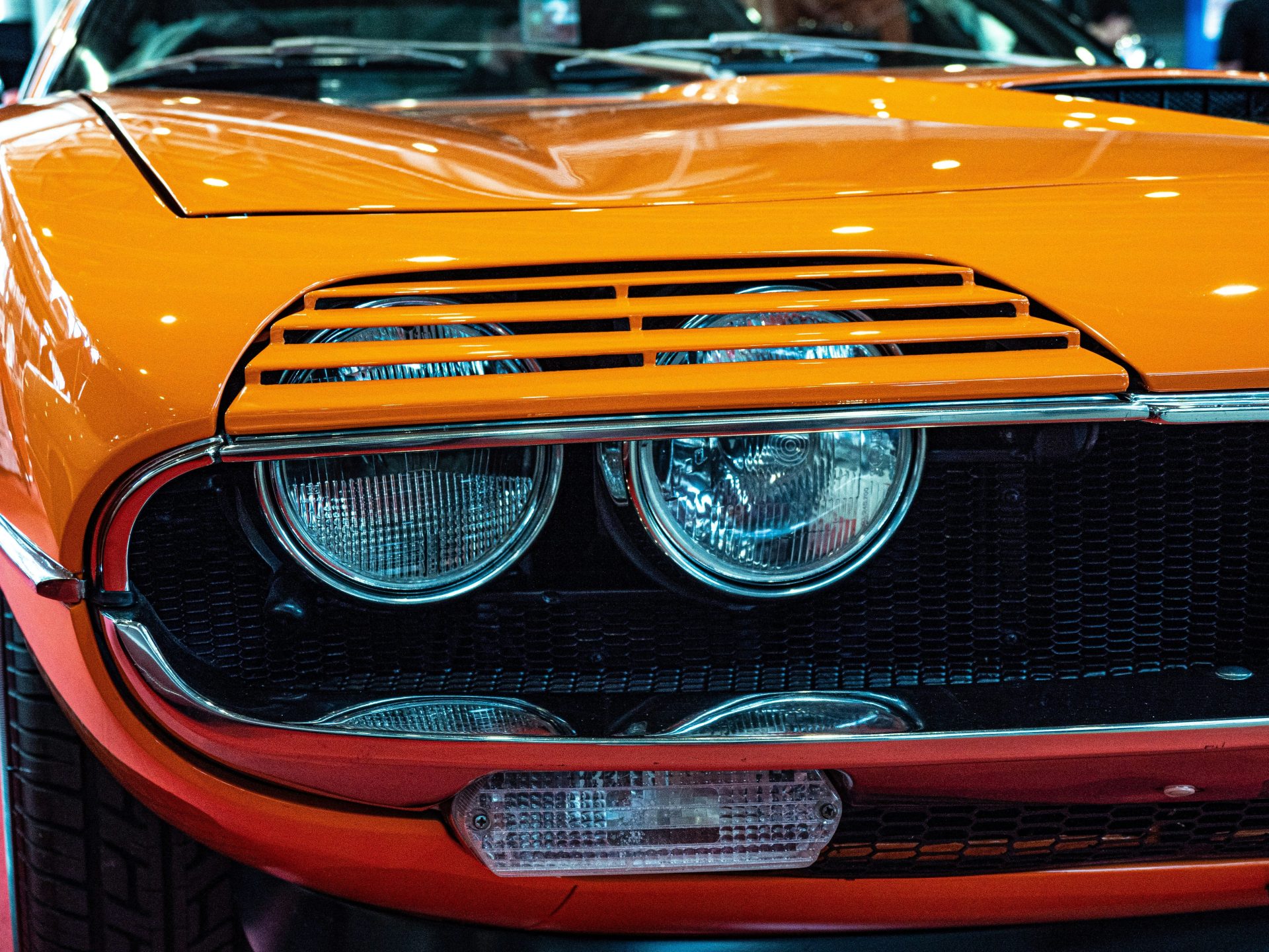 Here's a caption for the image: **close-up of an orange classic car.**